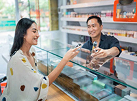 woman being e-cigarette from man in store