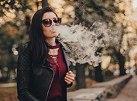 woman blows vape smoke